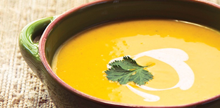 carrot parsnip soup with yogurt and cilantro leaf on top