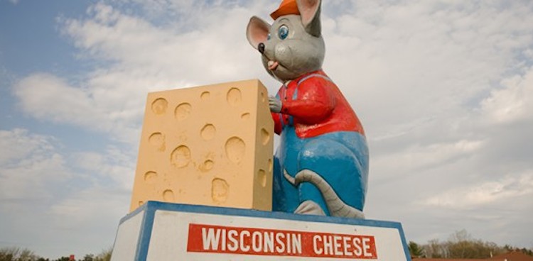 Roadside statue of a huge mouse dressed in a red shirt and cap with a huge piece of Swiss atop a Wisconsin Cheese sign