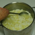 whey being ladled from pot of curds