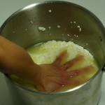 curds being pressed in pot with a hand