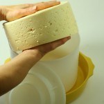 Cheese being removed from mold and flipped