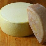red rinded port salut cheese leaning against yellow port salut cheese
