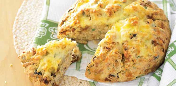 A crusty and cheese covered loaf of olive damper bread from Australia