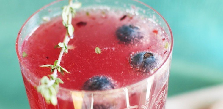 Cocktail in clear glass with blueberries and thyme