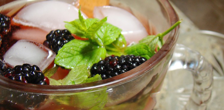 drink in clear glass with ice, mint, and blackberries