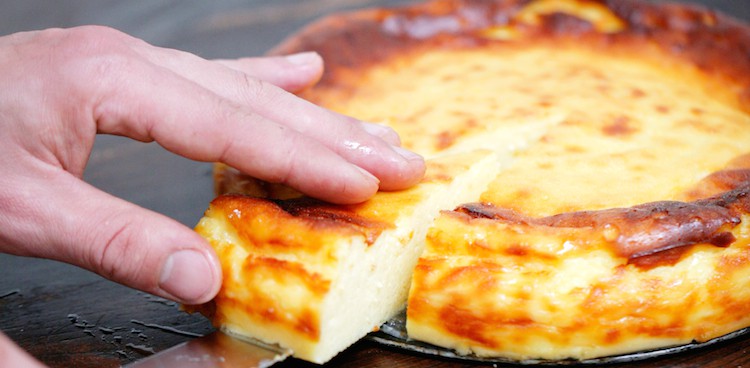 baked goat cheese tart with a browned top and a slice being removed from it