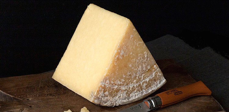 wedge of cheese on board next to knife