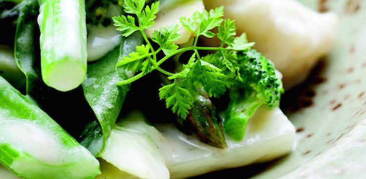 Green vegetables coated in a luscious cheese fondue sauce