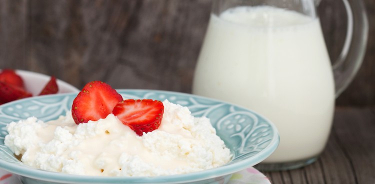 cottage cheese with strawberries on top with a pitcher of milk in the background