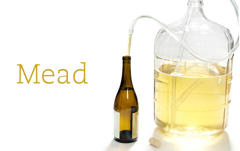 A carboy of mead is attached via plastic tube to a large bottle.