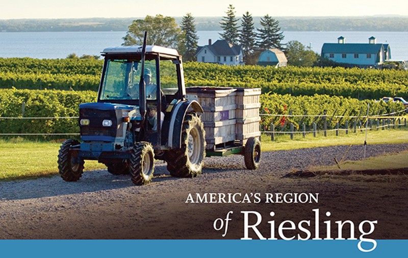 A tractor hauls wooden cartons of grapes before a stunning vista of a vineyard on the shores of a New York lake.