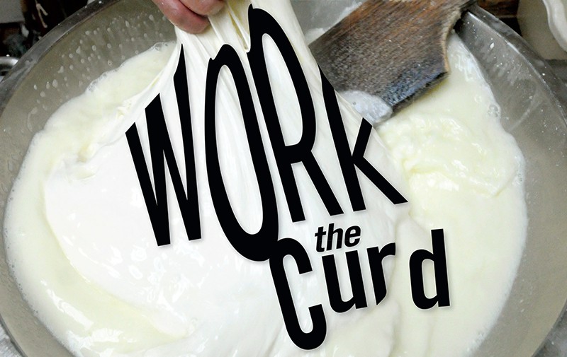 A cheesemaker pulls a big fold of mozzarella