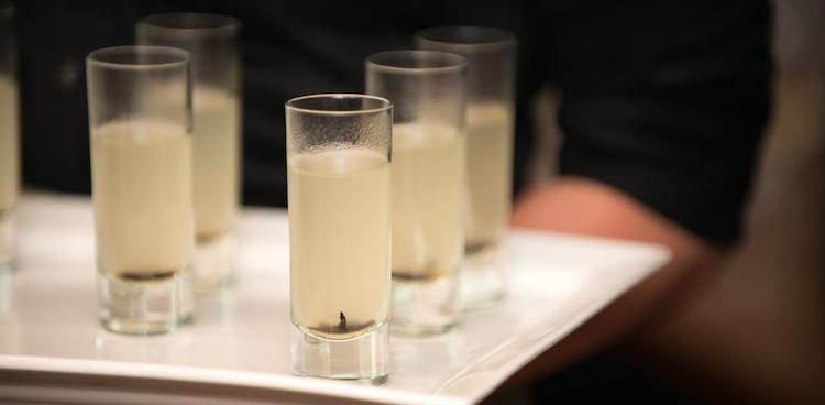 tall shot glasses of brodo de parmigiano reggiano (parmesan broth) with black mushroom in each