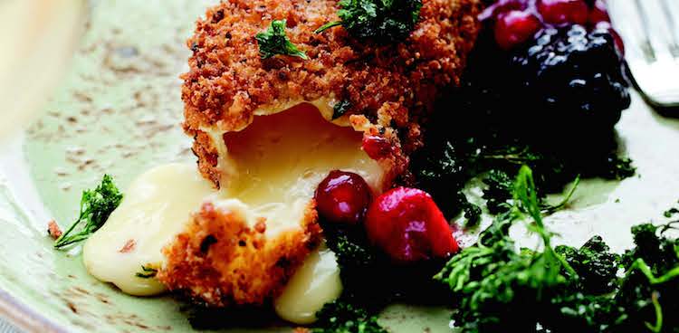 Cheese oozing from a deep-fried crispy panko crust with a side of parsley and berries