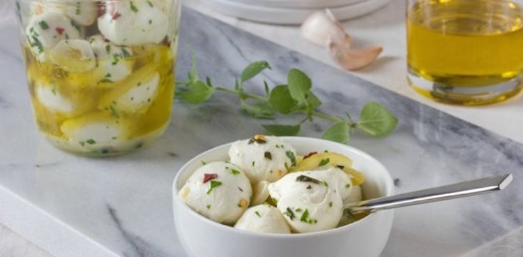 marinated mozzarella in bowl with glass jar in background