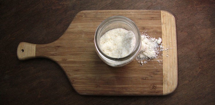 powdered parmesan in jar atop wooden cutting board with handle