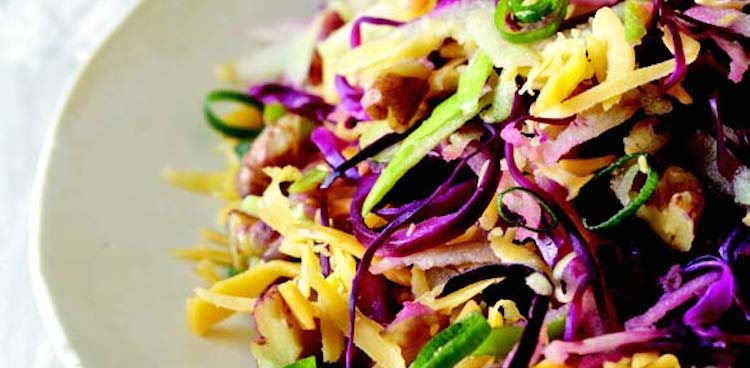 bowl of winter coleslaw with yellow cheddar, red cabbage, and green onion