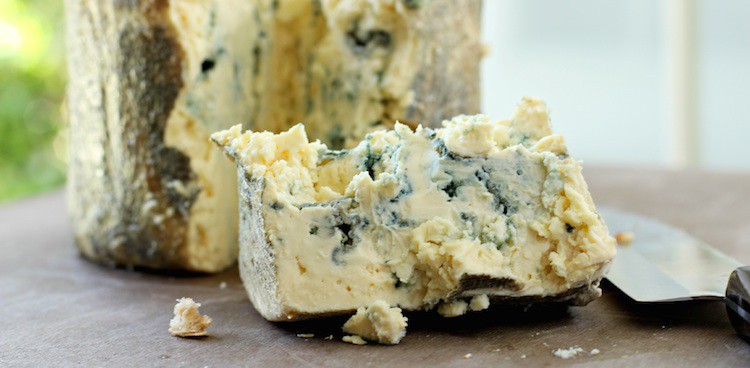 Creamy, leaf-wrapped blue cheese broken apart with a knife