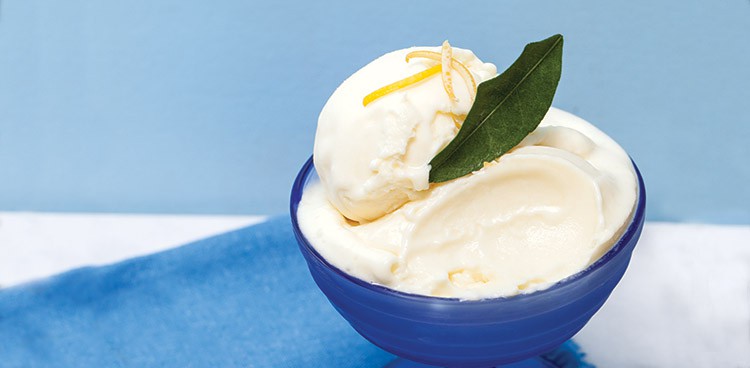 Lemon mascarpone ice cream in a bowl topped with lemon zest and garnished with a bay leaf