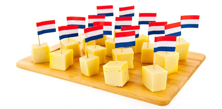 a cheese board covered in cheese cubes, each with a tiny French flag planted in it