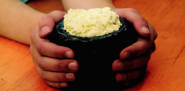 child's hands holding a bowl filled with homemade ricotta cheese