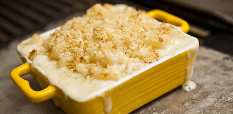 Baked four cheese macaroni and cheese in an enamel baking dish topped with Parmigiano Reggiano bread crumbs