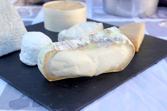 A slice of Puits d'Astier oozes on a cheese plate