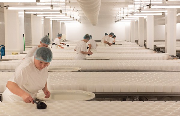 E. Graindorge workers hand-ladle curds into forms for Camembert de Normandie