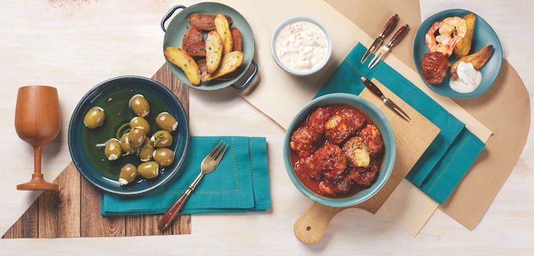 a tapas spread with fried potatoes, cheese stuffed olives, cheesy meatballs, and garlic shrimp