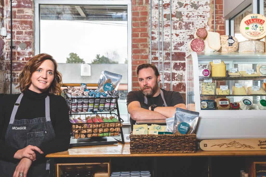 Michelle and Stevie Webb, owners of the Cheese Shop and the soon-to-be-open Wedgewood in Carrboro, North Carolina lean against a counter around many jams and cheeses.