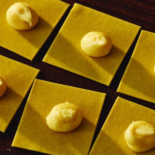 Balls of cheese fondue fillings sit on open pasta squares.